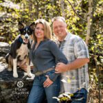 Fall couples portrait with their dog and a really big rock with fall leaves surrounding them. Laurel Danley Black Hills Photographer
