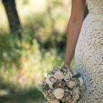 Detail image of the brides side of her dress with the lace and her wooden flower bouquet