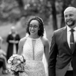 Black and white image of the bride and groom walking down the isle right after they got married. The smiles on their faces are full of Joy.