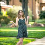 Senior girl posing on a sidewalk with a retro lamp post in the background with a cute short black flowy dress. Black Hills Photographer Laurel Danley