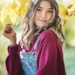 Senior Girl posing with fall leaves outdoors smiling headshot senior photos pictures red shirt blue overalls senior photos pictures summer day